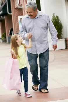 Grandfather With Granddaughter Carrying Shopping Bags