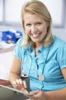 Female Doctor In Surgery Using Digital Tablet