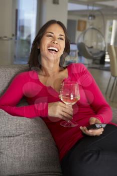 Hispanic Woman On Sofa Watching TV Drinking Wine