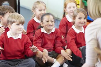 Pupils Sitting On Mat Listening To Teacher