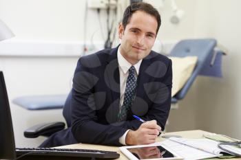 Portrait Of Male Consultant Working At Desk In Office