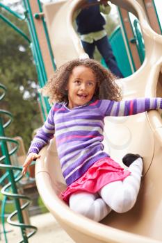 Young Girl Playing On Slide In Playground