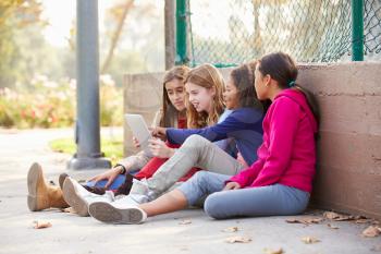 Group Of Young Girls Using Digital Tablet In Park
