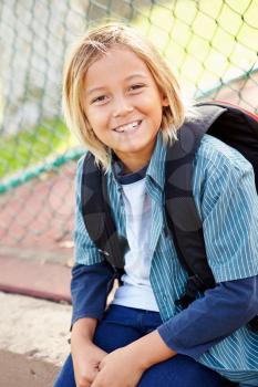 Portrait Of Young Boy With Rucksack Sitting In Park
