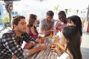 Group Of Friends Enjoying Drink At Outdoor Rooftop Bar