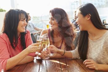 Three Female Friends Enjoying Drink At Outdoor Rooftop Bar