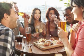 Group Of Friends Enjoying Drink And Snack In Rooftop Bar