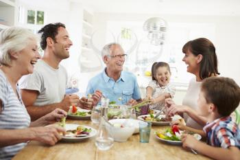 Multi Generation Family Eating Meal Around Kitchen Table