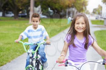 Two Hispanic Children Riding Bikes In Park