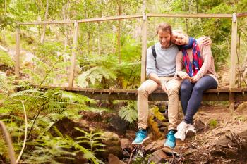 Happy couple relaxing on a bridge in a forest