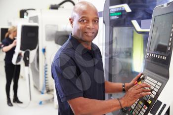 Portrait Of Male Engineer Operating CNC Machinery In Factory