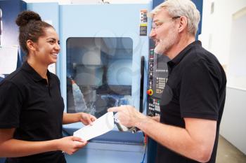 Female Apprentice Working With Engineer On CNC Machinery