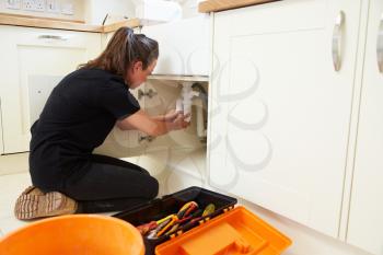 Female plumber fixing a kitchen sink