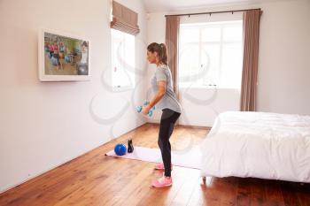 Woman Working Out To Fitness DVD On TV In Bedroom
