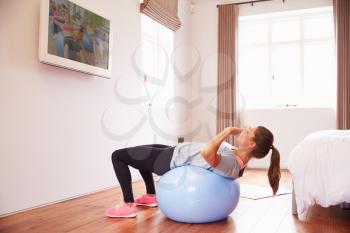 Woman On Ball Working Out To Fitness DVD On TV In Bedroom