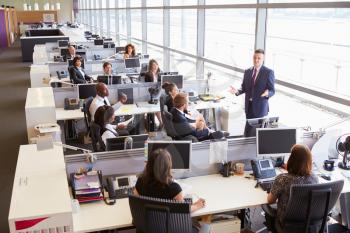 Young male manager addressing workers in open plan office