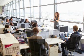 Female manager addressing workers in open plan office