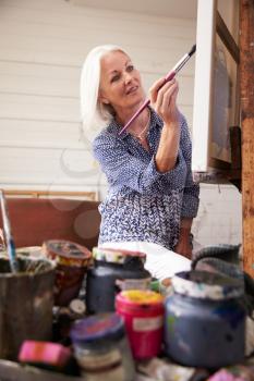 Female Artist Working On Painting In Studio