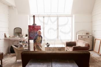 Female Artist Working On Painting In Bright Daylight Studio
