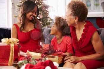 Girl With Grandmother And Mother Opening Christmas Gifts