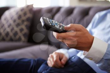 Close Up Of Man Sitting On Sofa Holding TV Remote