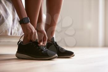 Young black woman tying sports shoes, close-up