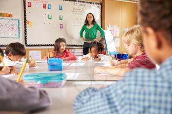 Teacher instructing elementary school kids in classroom