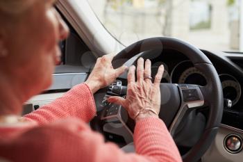 In car view of senior female driver using the horn in a car