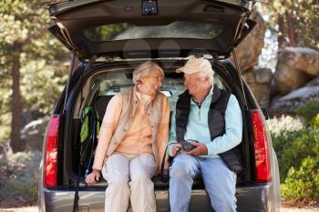 Senior couple sit in open car trunk before a hike, close-up