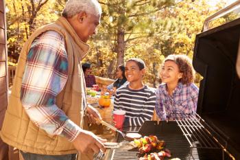 Grandparents With Children Enjoying Outdoor Barbecue