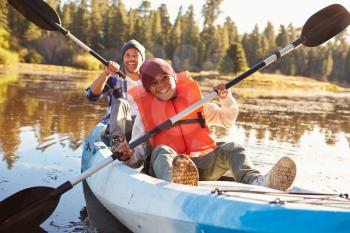 Father And Son Rowing Kayak On Lake