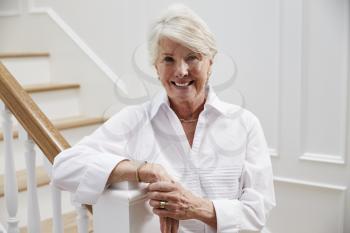 Portrait Of Senior Woman Standing By Staircase At Home