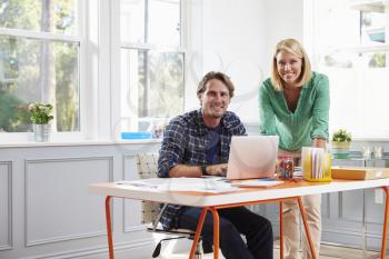 Portrait Of Couple Working Together At Desk In Home Office