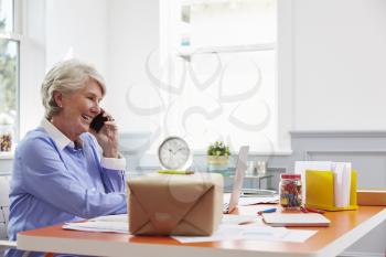 Senior Woman At Home Booking Courier Collection For Package