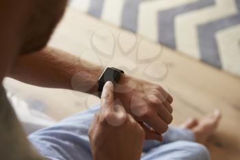 Man Wearing Pajamas Checking Smart Watch In Bedroom