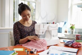 Woman Making Clothes Using Sewing Machine At Home