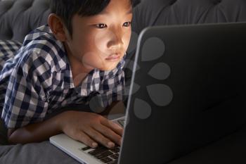 Boy Relaxing On Sofa At Home Using Laptop
