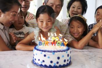 Girl Blows Out Candles At Family Birthday Celebration