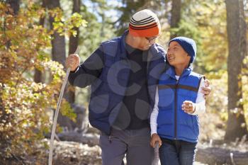 Dad and son hiking in forest embrace looking at each other