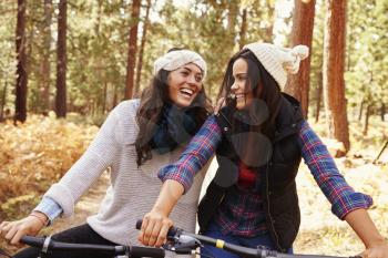 Lesbian couple on bikes in a forest looking at each other