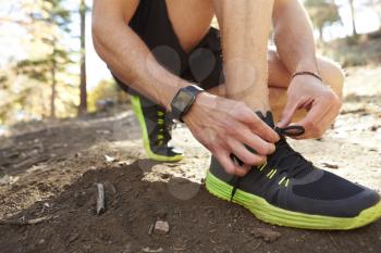 Man ties sports shoe before run in a forest, close up detail