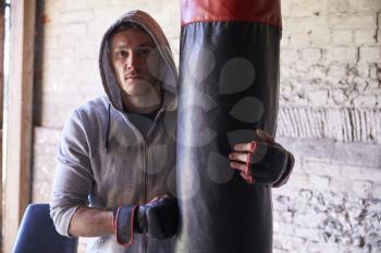 Portrait Of Young Male Boxer With Punch Bag In Gym