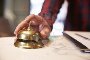 Close Up Of Guest's Hand On Hotel Reception Bell