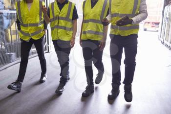 Four colleagues walk in an industrial interior, low section