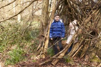 Brother and sister in a forest shelter made of tree branches