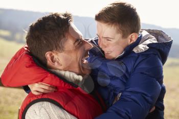 Father carrying son outdoors in countryside, close up