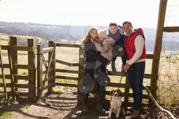 Happy family with dog by a gate in the countryside