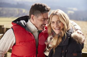 Couple wearing coats embracing in the countryside