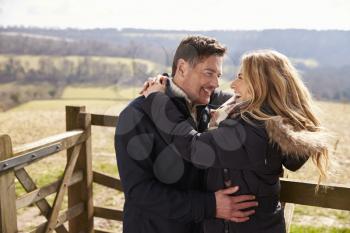 Happy couple embracing by a gate in the countryside