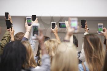 Young adults with arms raised take pictures with smartphones